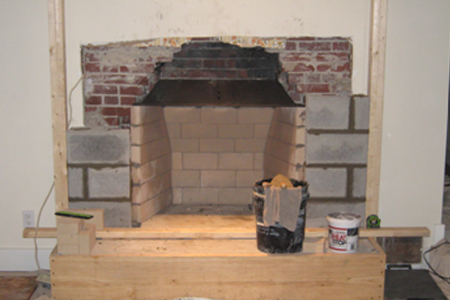 A fireplace with brick walls and a bucket of chips.