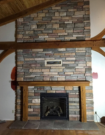 A fireplace with wood mantle and brick surround.