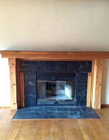 A fireplace with wood mantle and hearth in the center.