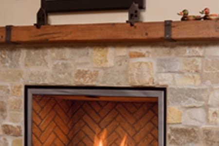 A fireplace with brick and stone surround, fire place mantel.